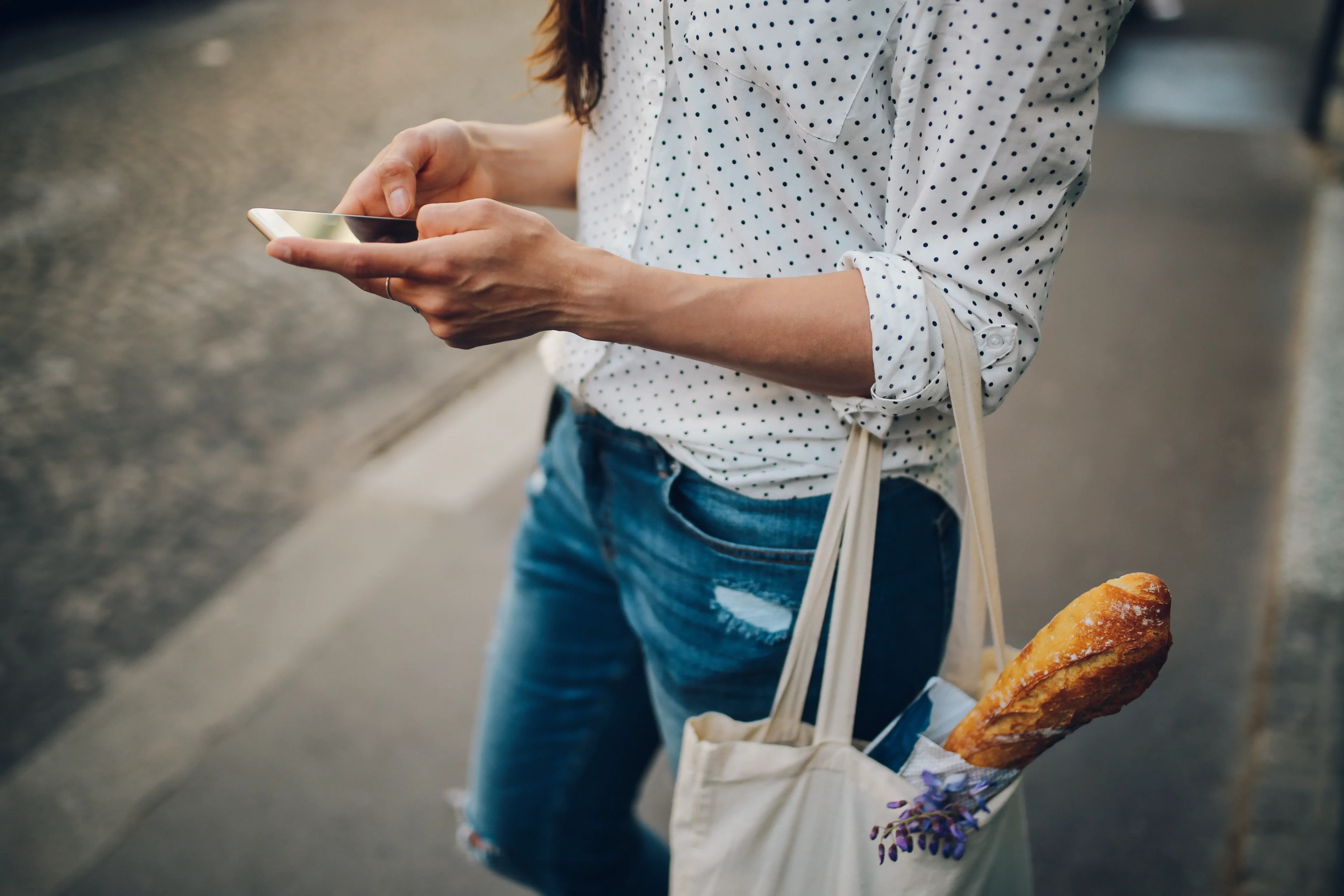 Eine Person mit Smartphone und Stofftasche