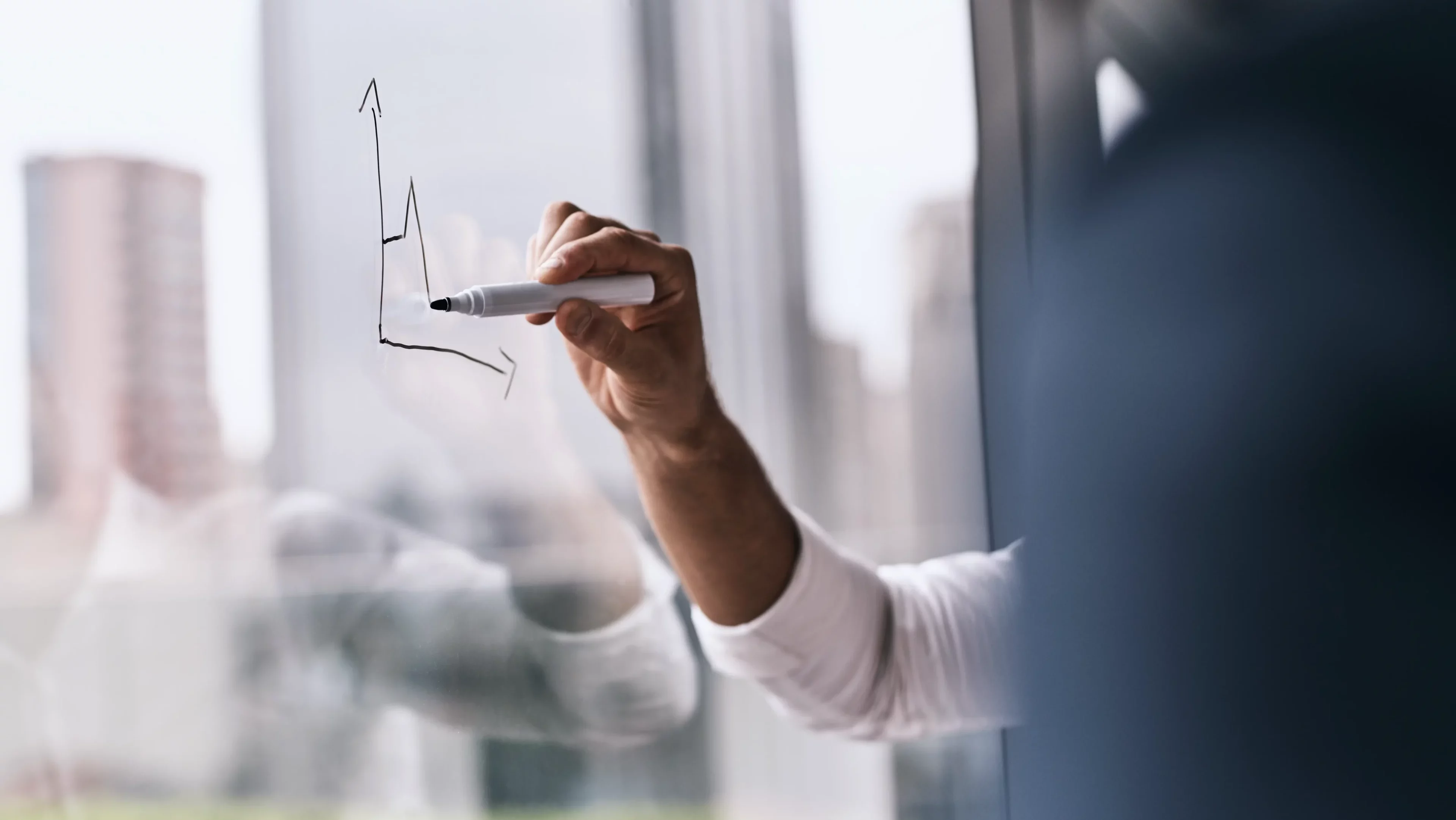 Person malt mit einem Stift auf ein Fenster einen Graphen